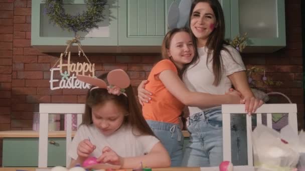 Una madre y sus dos hijos se están divirtiendo y pintando huevos de Pascua. Una familia feliz. — Vídeos de Stock