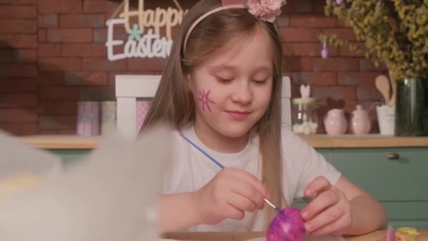 Niño feliz está pintando huevos de Pascua en la cocina en casa. — Vídeo de stock