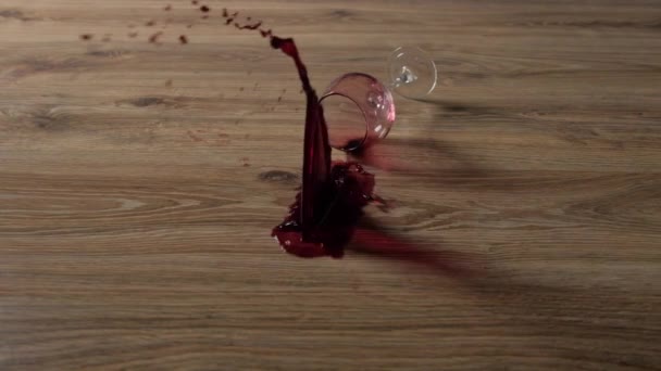 Бокал красного вина падает на ламинат в замедленной съемке — стоковое видео