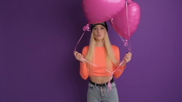 Kiev, Oekraïne - 20 december 2020: Gelukkige blonde met hartvormige ballonnen in de studio op een violette achtergrond. — Stockvideo