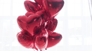 Yüzen bir buket kırmızı, beyaz arka planda kalp şeklinde balonlar..