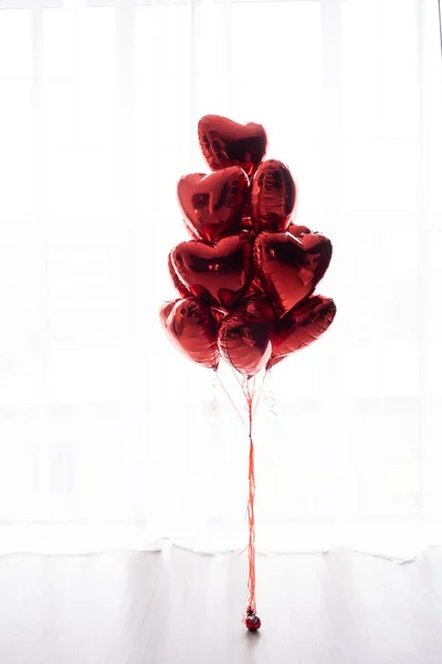 Um buquê flutuante de balões vermelhos em forma de coração sobre um fundo branco. — Fotografia de Stock