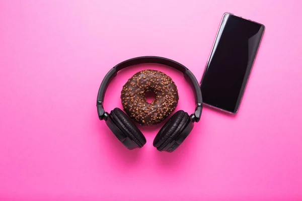 Donut and headphones on a pink background. Concept of business lunch and rest after work. — Stock Photo, Image