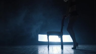 Seksi bir kızın silueti mavi dumanla erotik bir dans ediyor..