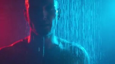 Siyah bir arka planda, sisli ve neon ışıklı duşta gaza gelmiş genç bir adamın portresi..