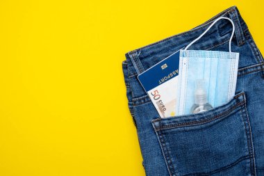 Kotlu pasaport parası ve koruyucu maskeli bir cep. Pandemik seyahat kavramı.