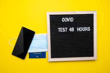 Coronavirus seyahat konsepti. Sarı arka planda pasaport maskesi ve para. 48 saat metin covid.
