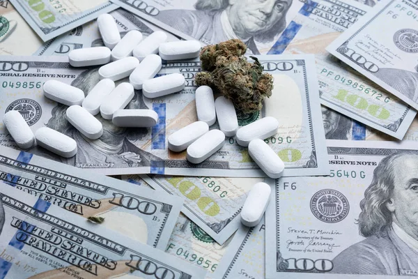 Marihuana de cannabis y pastillas narcóticas en el fondo del primer plano del dólar. — Foto de Stock