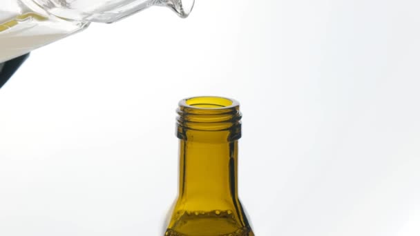 L'olio vegetale viene versato in una bottiglia su uno sfondo bianco primo piano. — Video Stock