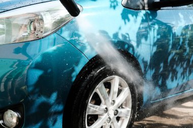 Evde tek başına araba yıka. Araba yıkama yüksek basınç yakın çekim. Bir adam yeşil bir arabayı yıkıyor..