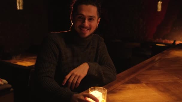 夜のバーで若い男の肖像画。男はカクテルを飲んで休み. — ストック動画