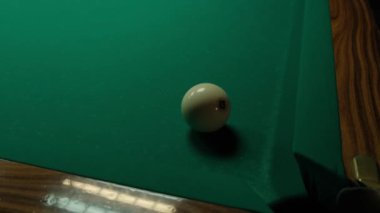 Karanlık bir odada yeşil bir masada bilardo oynamak. Adam toplara ıstakayla vuruyor ve deliğe vuruyor.