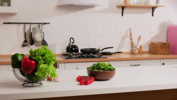 Ensalada de verduras frescas, pimientos verdes y rojos y tomates cherry sobre una mesa sobre un fondo de cocina blanco. — Vídeo de stock