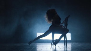 Seksi bir kızın silueti mavi dumanla erotik bir dans ediyor..