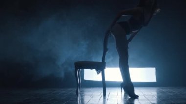 Seksi bir kızın silueti mavi dumanla erotik bir dans ediyor..