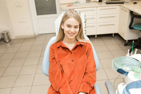 A menina é uma loira com um sorriso agradável na consulta de dentistas. — Fotografia de Stock