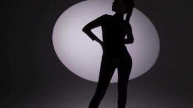 Siyah arka planda lateks kıyafetli bir kadının silueti.