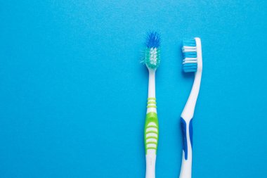 Mavi arka planda kullanılmış eski ve yeni diş fırçası.