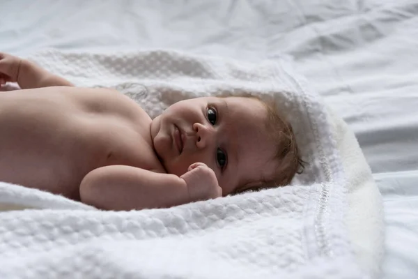 Egy hónapos kislány fehér lepedőn. Fényben forgatva — Stock Fotó