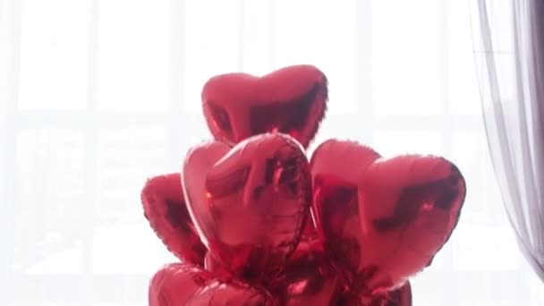 Un bouquet flottant de ballons rouges en forme de cœur sur fond blanc. — Video