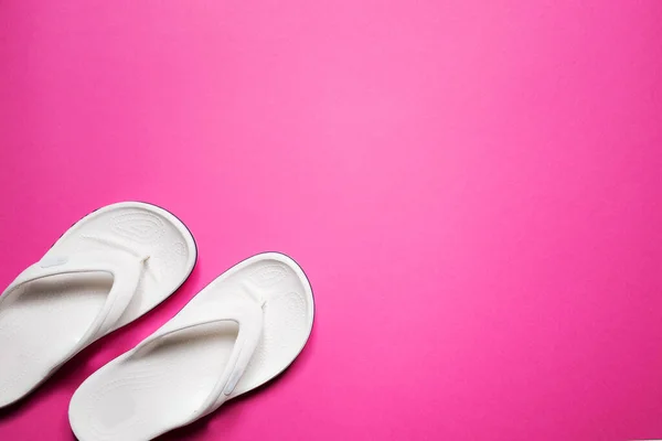 Chanclas sobre un fondo rosa aislado. Chanclas blancas femeninas. — Foto de Stock