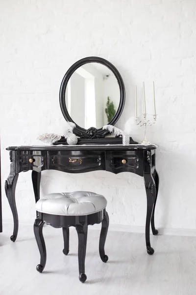 Black boudoir table in a bright room with a white brick wall. — Zdjęcie stockowe