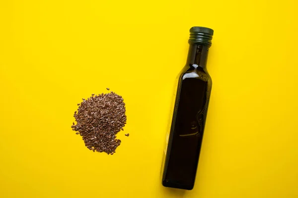 Linseed oil on a yellow background. Dark colored oil bottle. — Stock Photo, Image