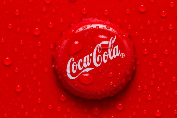 Kiev, UKRAINE - 28 Ocak 2019: klasik Coca-Cola kapağı. Kırmızı zemin üzerinde su damlaları olan bir kola kapağı.