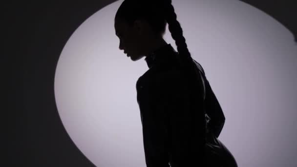 Silhueta de uma mulher em um terno de látex em um fundo escuro — Vídeo de Stock