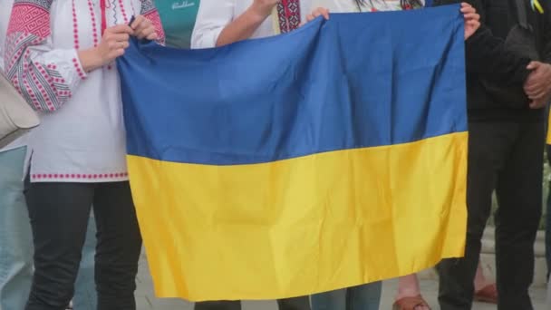 Women hold the Ukrainian flag at a rally against the war. — Video