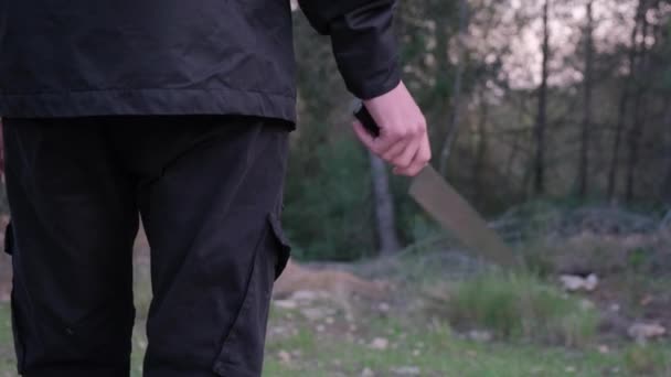 Человек с ножом в лесу. Маньяк преследует жертву и готовится к нападению — стоковое видео