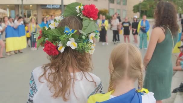Tarragona, Spanje - 15 mei 2022: Portret van een Oekraïense vrouw op een bijeenkomst ter ondersteuning van Oekraïne. Meisje met een krans op haar hoofd en de vlag van Oekraïne. — Stockvideo