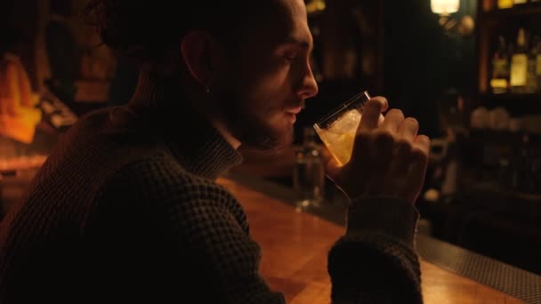 Портрет молодого парня в ночном баре. Человек пьет коктейль и отдыхает.. — стоковое видео
