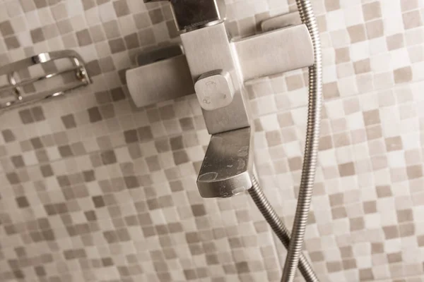 Water tap in the bathroom close-up. Hard water. Plaque on the tap from dirty water. Tile in the bathroom.