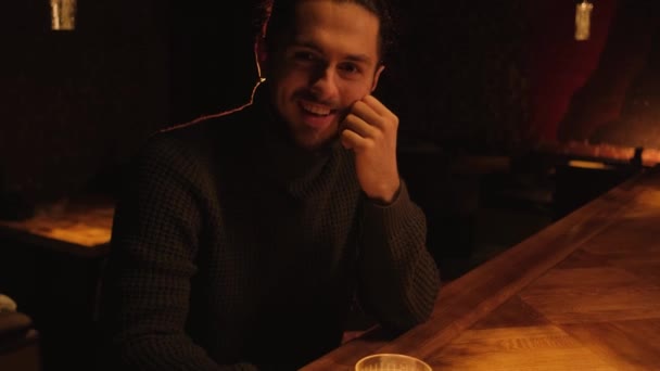 夜のバーで若い男の肖像画 男はカクテルを飲んで休み — ストック動画