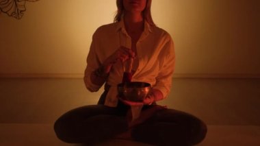 Elinde Tibet şarkı kasesi olan Yogi bir kadın. Yoga odasında..