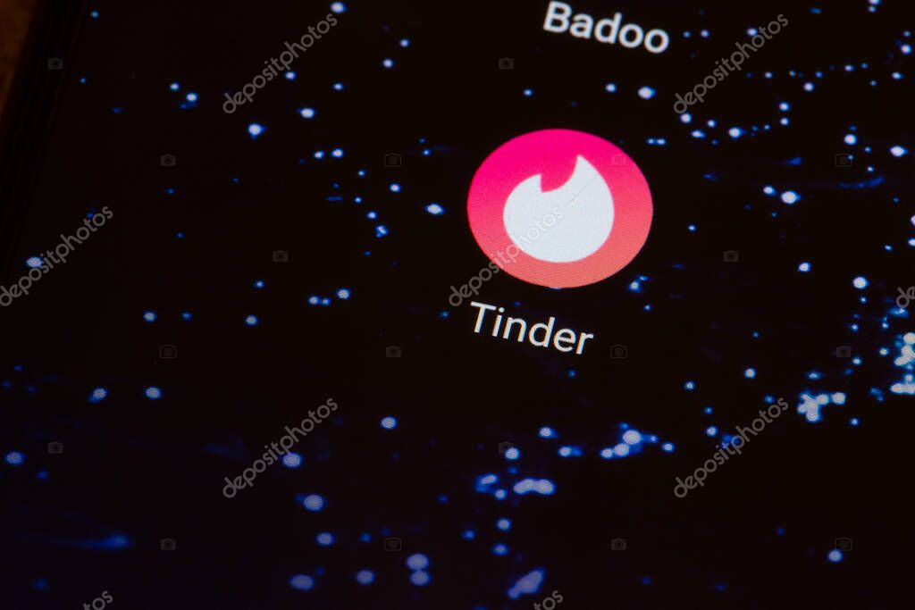 Kiev, Ukraine - March 27, 2021: Tinder logo on a dark smartphone screen close-up.