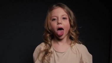 Küçük kız şaşırdı. Stüdyoda karanlık bir arka planda yakın plan portresi..