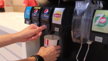 Tarragona, Spain - June 01, 2022: A mans hand pours a glass of Pepsi in a fast food restaurant. KFC fast food restaurant.