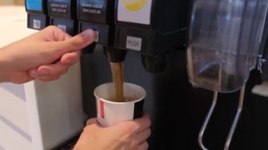 Tarragona, Spain - June 01, 2022: A mans hand pours a glass of Pepsi in a fast food restaurant. KFC fast food restaurant.