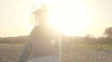 A girl with curly hair runs along the beach on a sunny day.