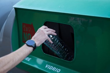 Adamın biri çöp kutusuna plastik şişe atıyor..