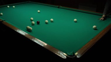 Karanlık bir odada yeşil bir masada bilardo oynamak. Adam toplara ıstakayla vuruyor ve deliğe vuruyor..