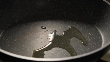 Zeytinyağı, arka planda yakın planda sıcak bir tavaya dökülür..