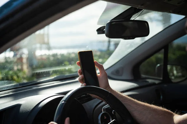 A driver with a phone in his hands while driving a car.