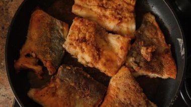 Evde, ocağın üstünde tavada balık kızartmak..