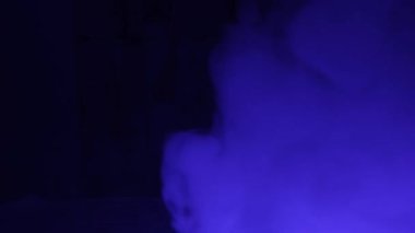 Koyu arkaplanda mavi renkli dumanın bulanık görüntü dokusu.