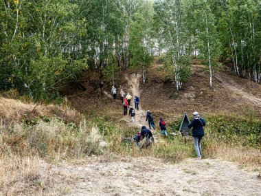 Turistler ormanlarla kaplanmış tepeye tırmanıyor. Güney Uralları, sonbaharın başlangıcı.