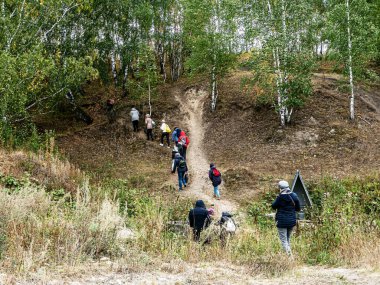 Turistler ormanlarla kaplanmış tepeye tırmanıyor. Güney Uralları, sonbaharın başlangıcı.