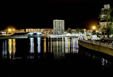 Sirk alanındaki Chelyabinsk şehrindeki Miass Nehri 'nin gece kıyısında suya, Rusya' ya ve Güney Urallar 'a çok renkli ışıklar yansıyor.